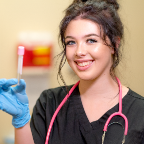 Medical Assistant Student holding up a vile in lab